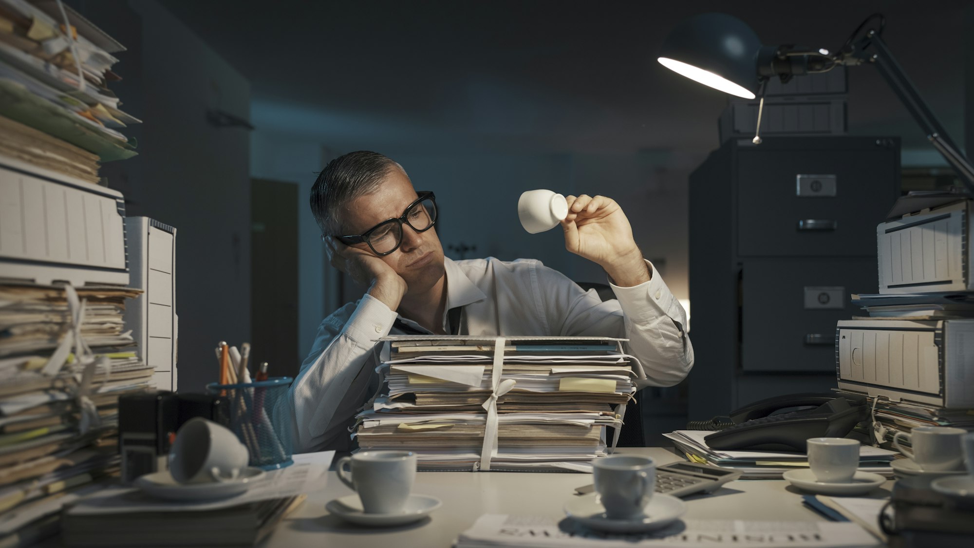 Sad office worker sitting at desk at night