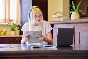Female student in headphones using a laptop, studying at home